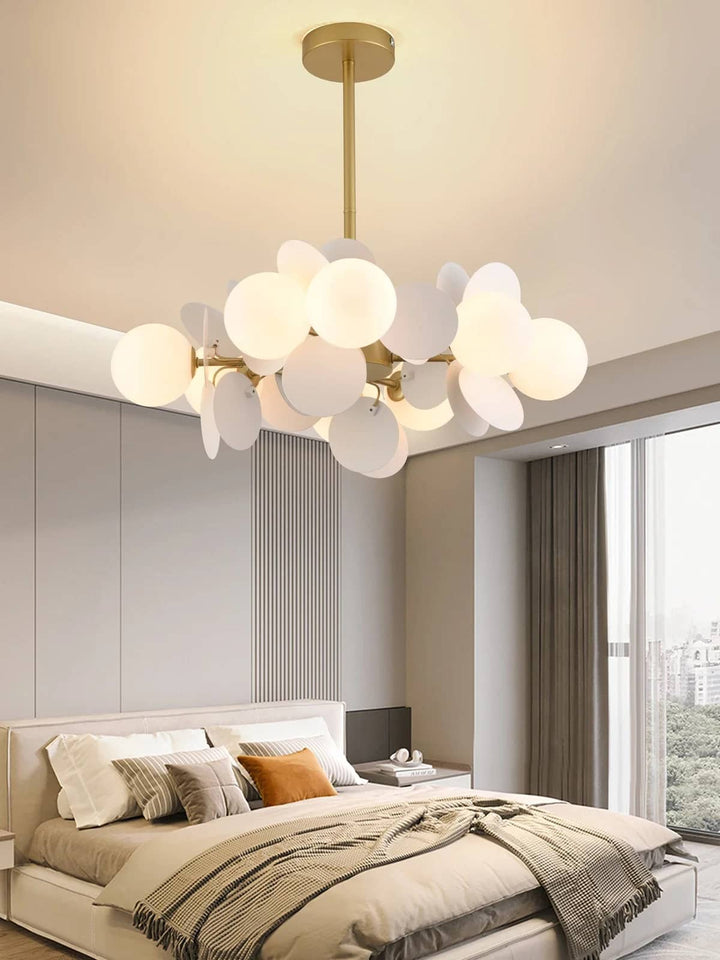 Suspension aérienne aux globes blancs diffusant une lumière douce dans une chambre à coucher minimaliste.