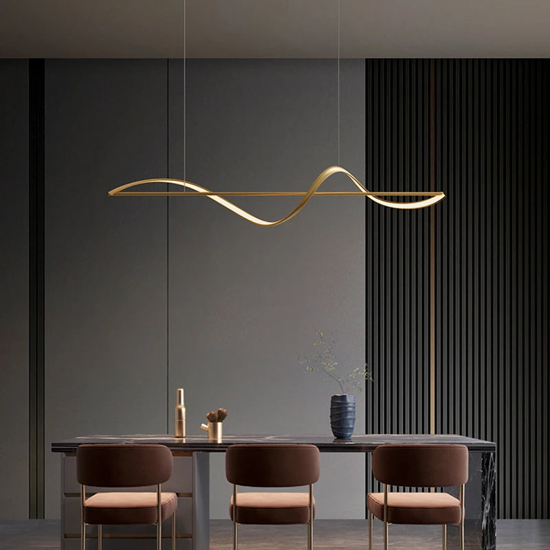 Luminaire suspendu au design moderne doté d'un ruban ondulé doré, idéal pour éclairer une grande table.