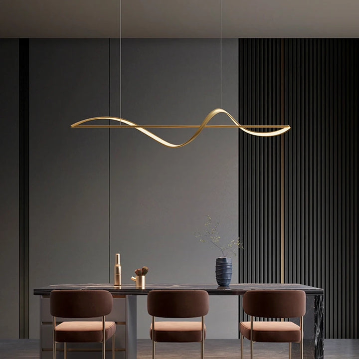 Luminaire suspendu au design moderne doté d'un ruban ondulé doré, idéal pour éclairer une grande table.