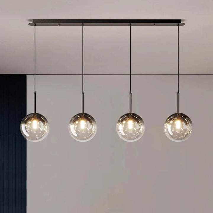 Luminaire suspendu design avec structure noire et abat-jour globes en verre fumé alignés.