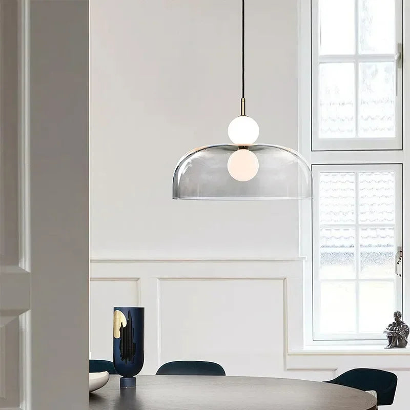 Aperçu à travers une porte d'un luminaire suspendu en forme de dôme contemporain en verre et structure dorée.