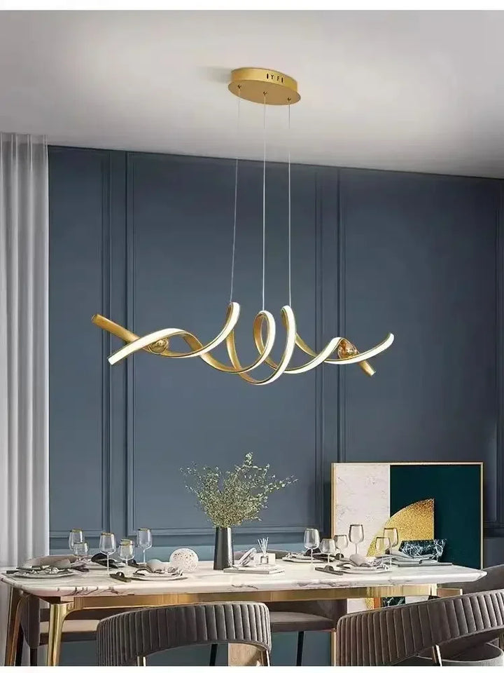 Superbe luminaire suspendu doré en volutes, sublimant une salle à manger chic aux murs bleu canard.