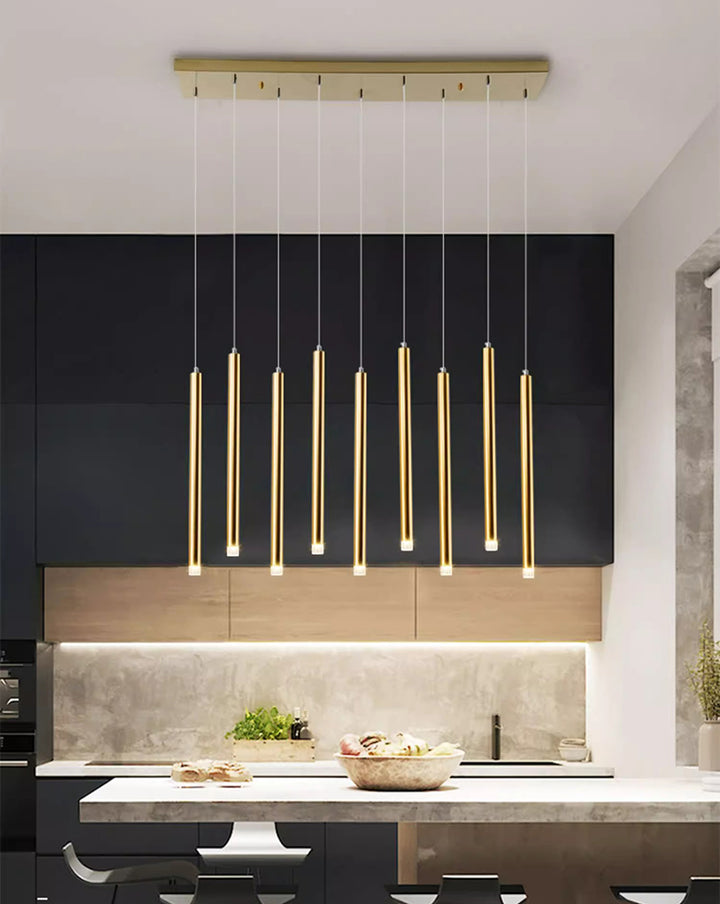 Luminaire suspendu à tubes lumineux dorés habillant élégamment le comptoir d'une cuisine moderne ouverte.