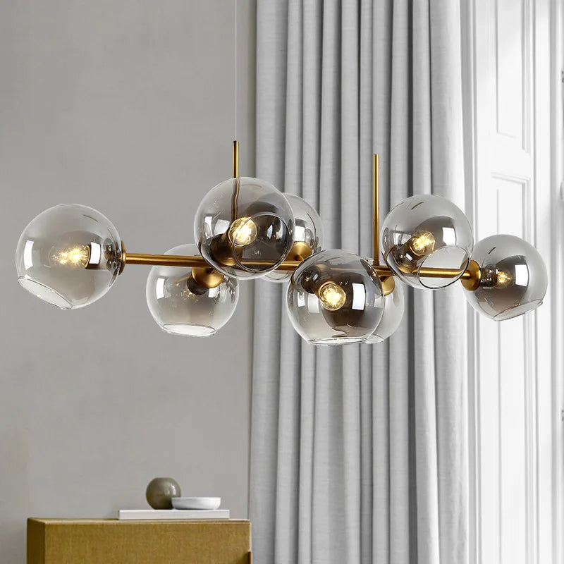 Luminaire suspendu moderne à multiples globes en verre et structure dorée dans un salon lumineux.