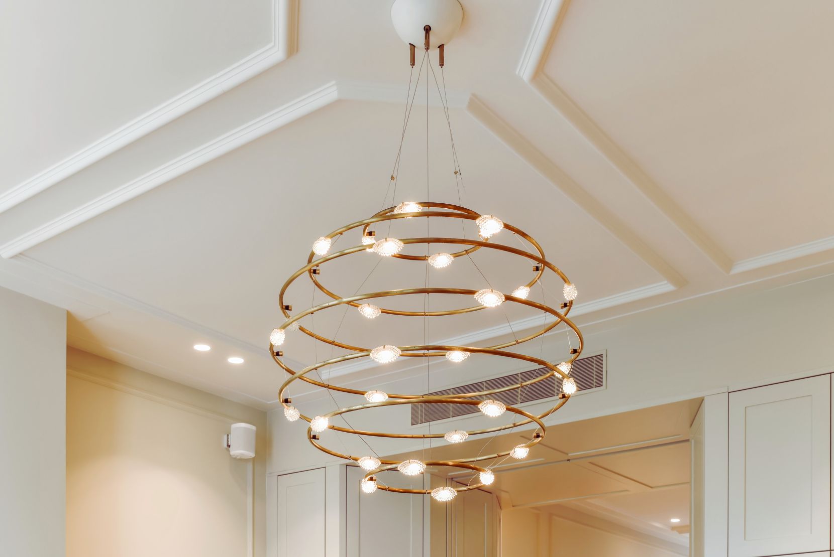 Suspension design en métal doré avec anneaux lumineux LED, idéale pour un éclairage élégant et moderne dans un salon ou une salle à manger.