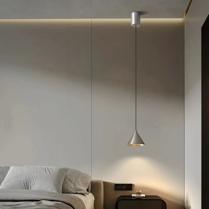 Luminaire suspendu moderne au design épuré, diffusant une lumière douce et chaleureuse dans une chambre contemporaine.