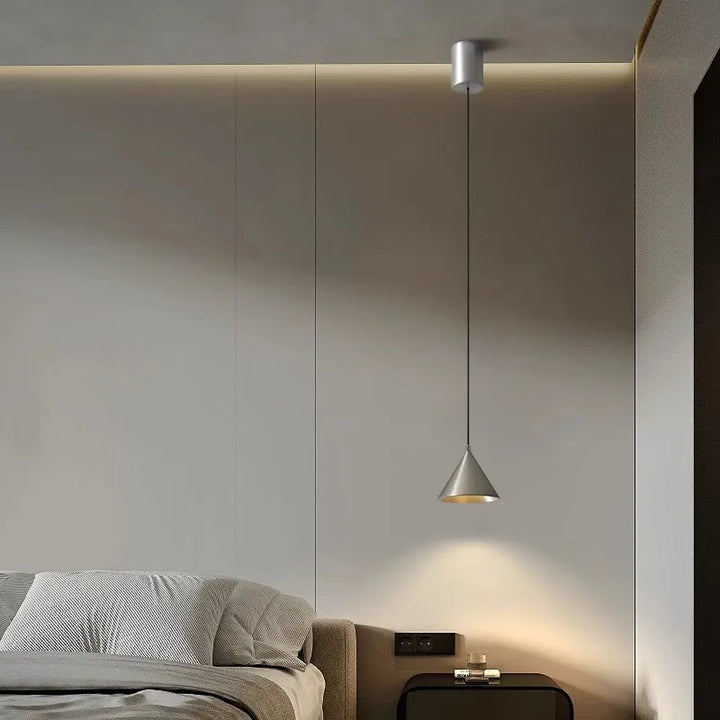 Luminaire suspendu moderne au design épuré, diffusant une lumière douce et chaleureuse dans une chambre contemporaine.