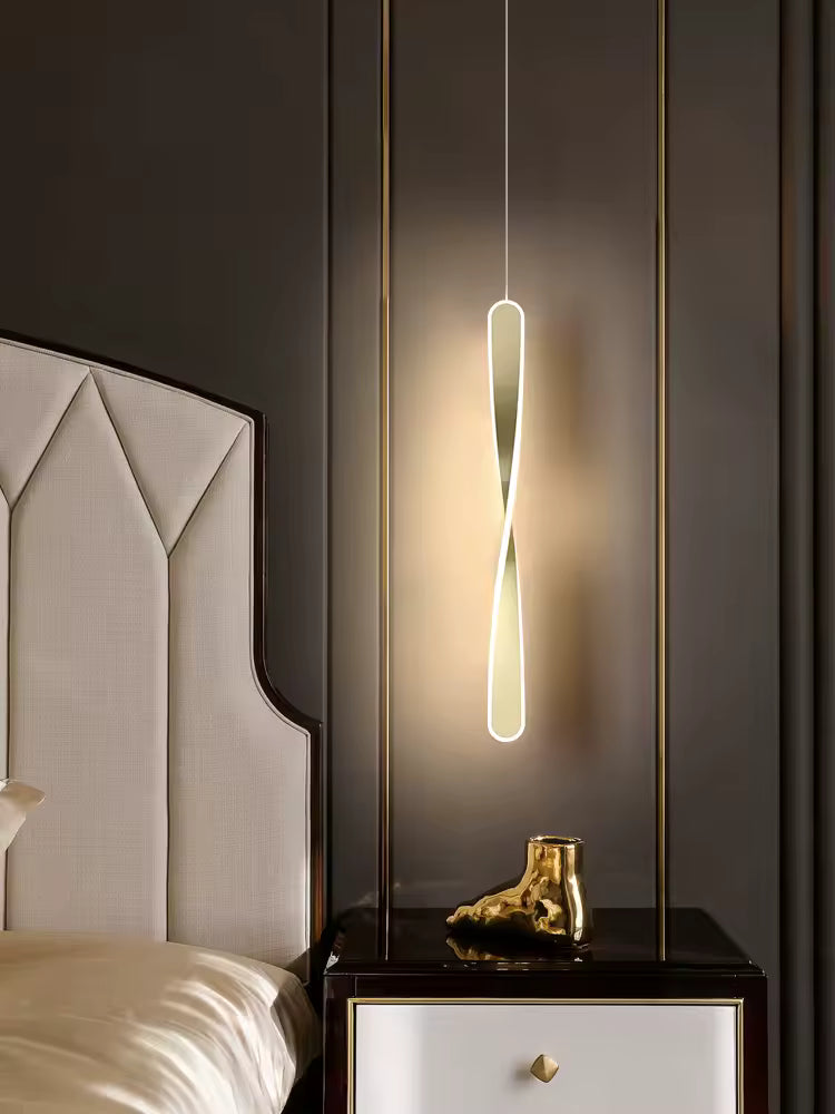 Suspendu près du lit, ce luminaire torsadé doré au contour lumineux apporte une touche élégante et contemporaine