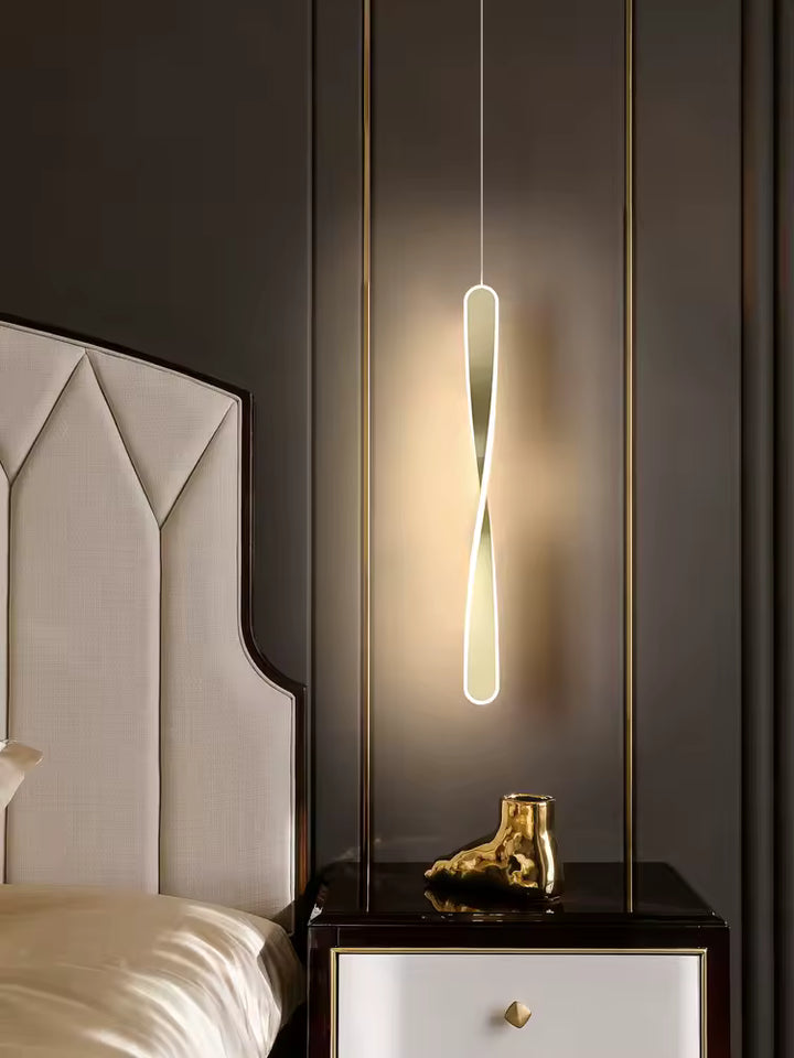 Suspendu près du lit, ce luminaire torsadé doré au contour lumineux apporte une touche élégante et contemporaine