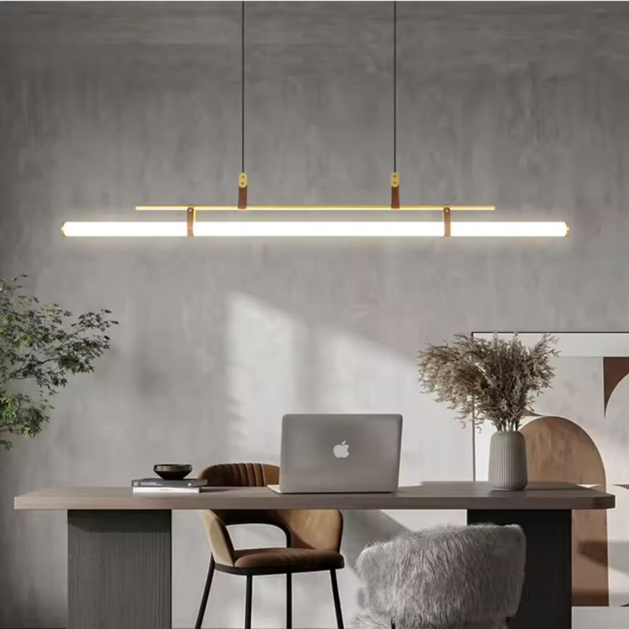 Luminaire linéaire LED doré avec attaches en cuir, suspendu au-dessus d’un bureau au style contemporain épuré