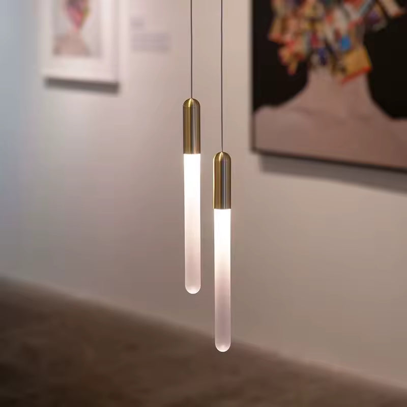 Deux diffuseurs tubulaires lumineux à finition dorée composent un luminaire minimaliste au dessin vertical et épuré