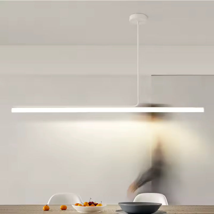 Luminaire tubulaire LED blanc au design épuré, suspendu au-dessus d’une table dans une salle à manger contemporaine.