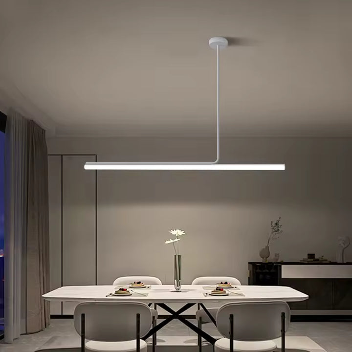 Une suspension tubulaire LED blanche surplombe la table et accentue l’ambiance sobre et minimaliste de la salle à manger.