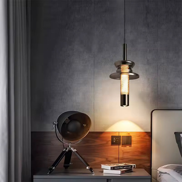 Près du lit, ce luminaire tubulaire en verre fumé et métal diffuse une lumière chaude au style industriel raffiné
