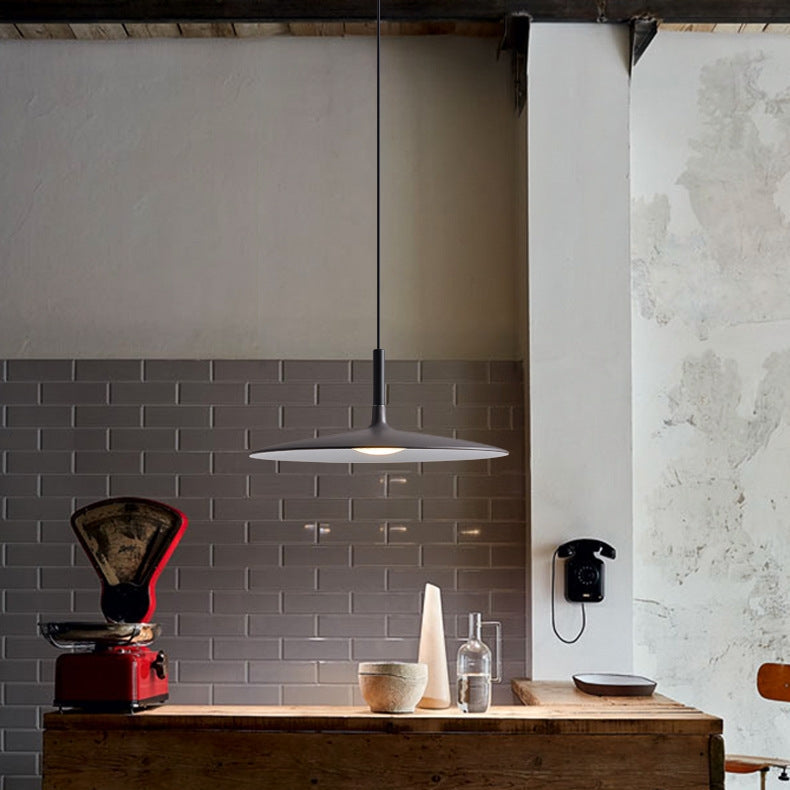 Ambiance chaleureuse avec luminaire UFO noir suspendu au-dessus d'un meuble en bois massif.