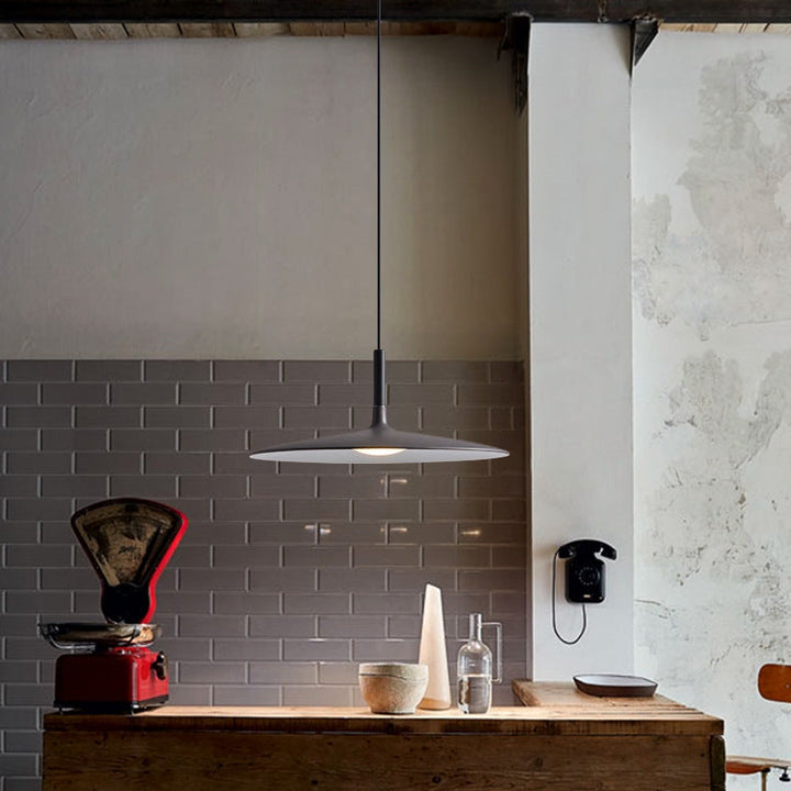 Ambiance chaleureuse avec luminaire UFO noir suspendu au-dessus d'un meuble en bois massif.