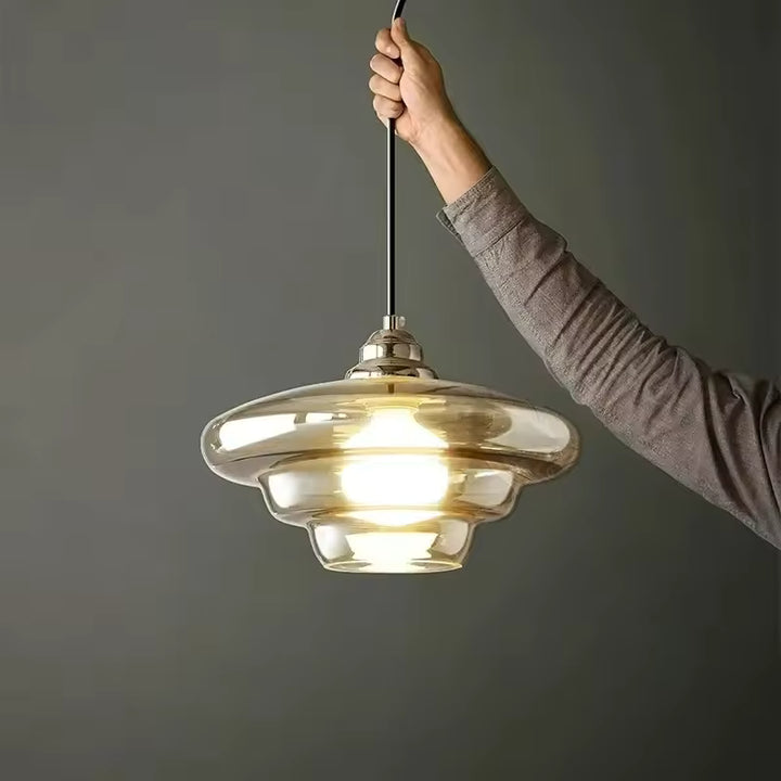 Vue rapprochée d’un luminaire en verre champagne à silhouette étagée, au design rétro et aux reflets chaleureux