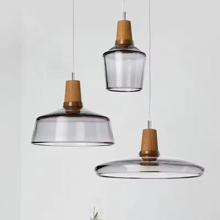 Trois formes de luminaire en verre fumé et bois associent transparence, lignes douces et design sculptural