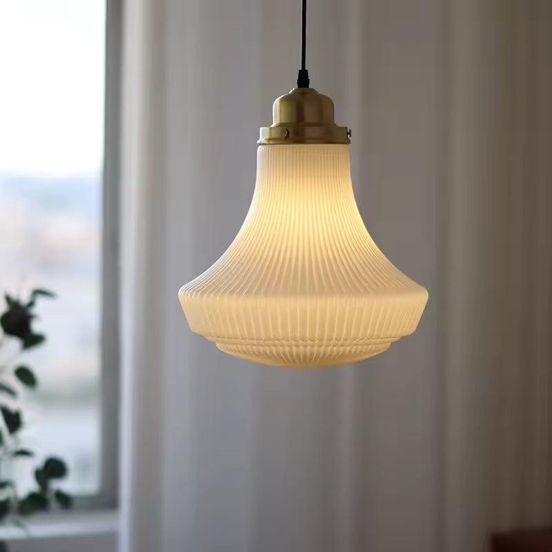 Éclairage suspendu en verre opalin nervuré à forme évasée, au charme rétro et à la lumière chaleureuse près d’une fenêtre