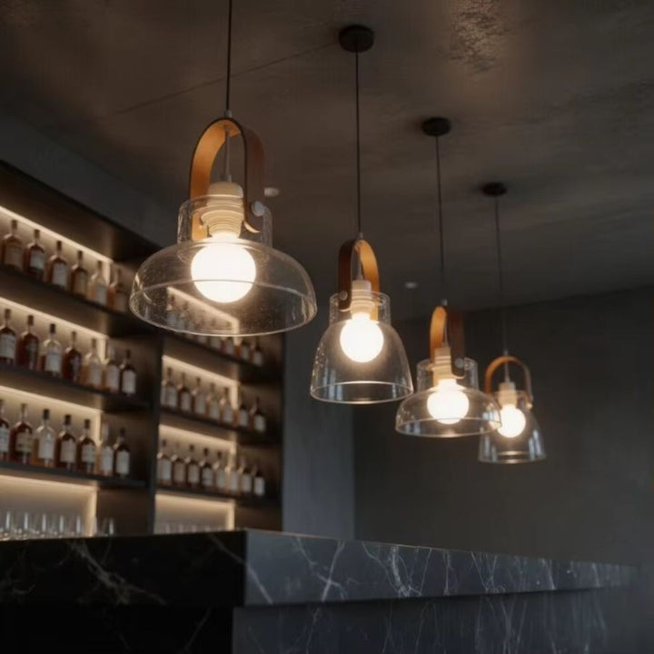 En enfilade, quatre luminaires en bois et verre soufflé éclairent un bar en marbre noir à l’atmosphère chic et feutrée