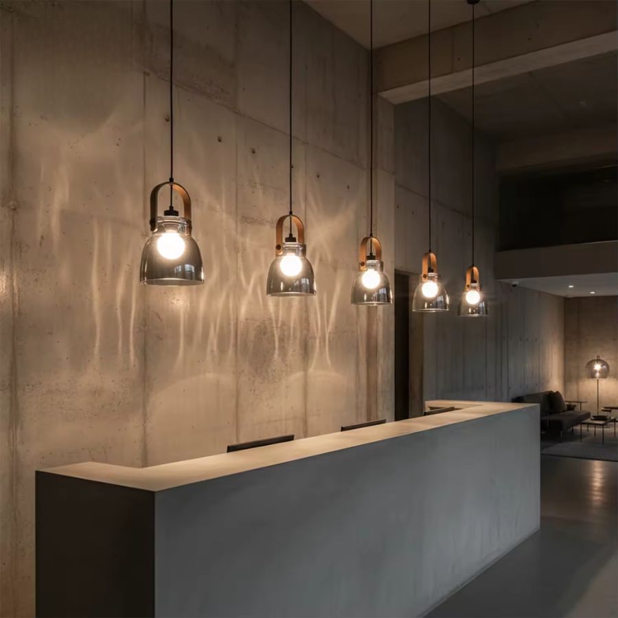 Une rangée de luminaires en bois et verre soufflé fumé éclaire un comptoir dans un intérieur industriel contemporain