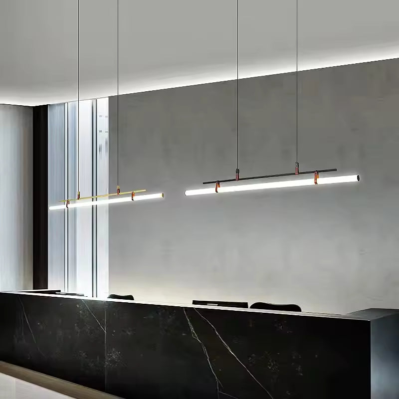 Deux suspensions tube néon LED, noir et doré avec attaches en cuir, suspendus au-dessus d’un îlot au style contemporain