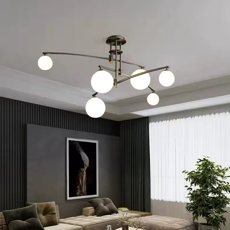 Lustre design contemporain à bras métalliques asymétriques et globes en verre blanc illuminant un salon élégant.