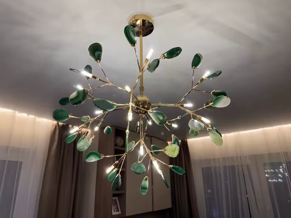Lustre en agate verte aux feuilles minérales éclairées, porté par une structure dorée au design végétal