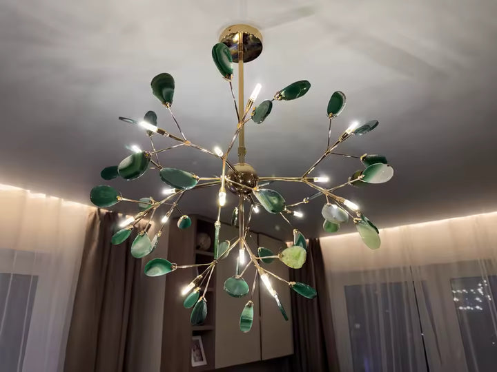 Lustre en agate verte aux feuilles minérales éclairées, porté par une structure dorée au design végétal