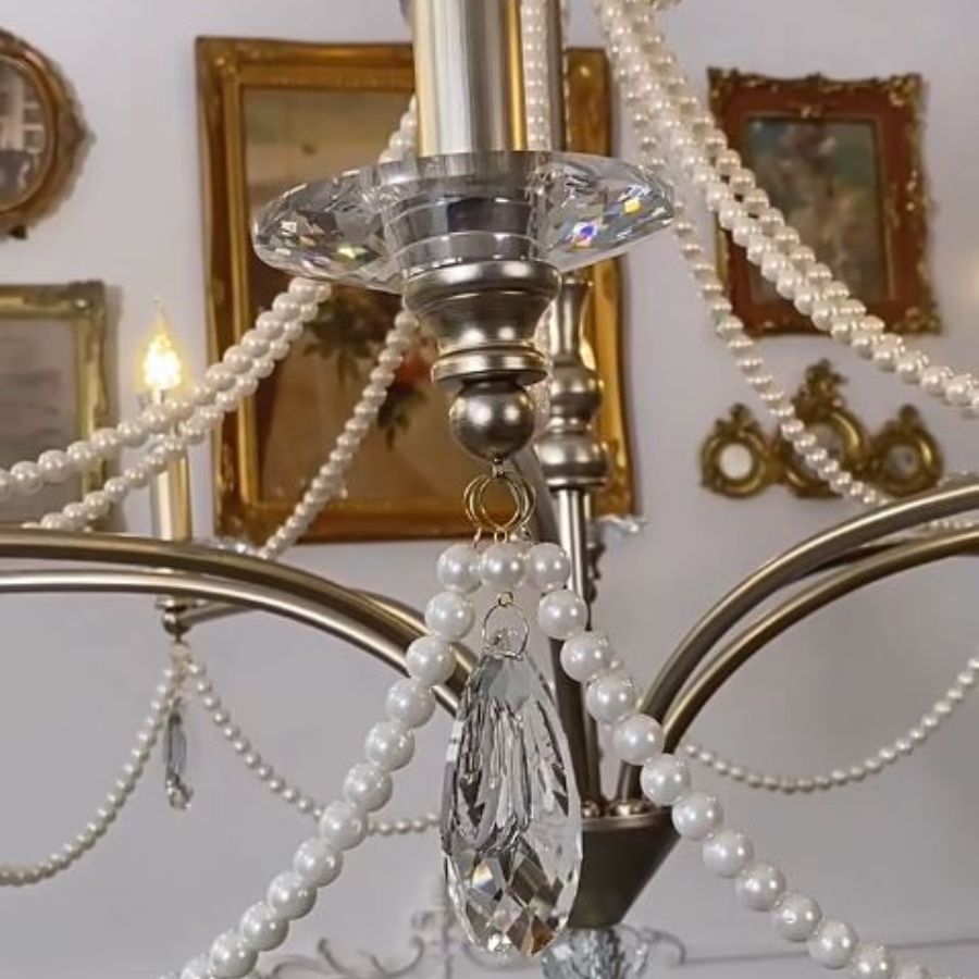 Gros plan sur les pampilles en cristal facetté et les guirlandes de perles nacrées d'un lustre argenté raffiné.