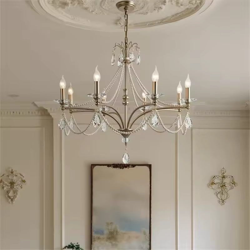 Lustre argenté à six branches et pampilles de cristal, sublimant une pièce de style classique chic aux murs moulurés.