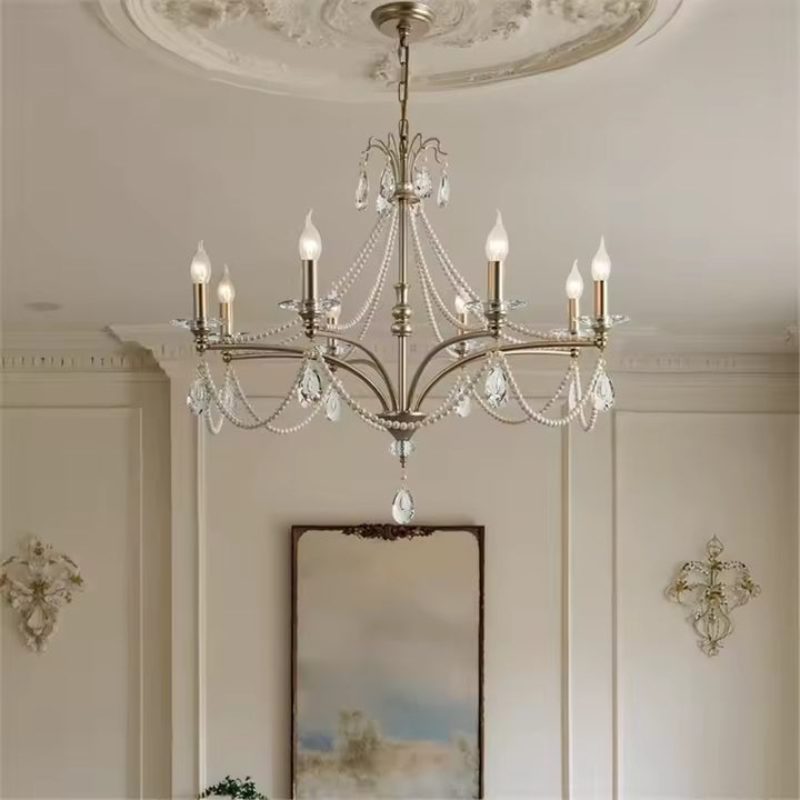 Lustre argenté à six branches et pampilles de cristal, sublimant une pièce de style classique chic aux murs moulurés.