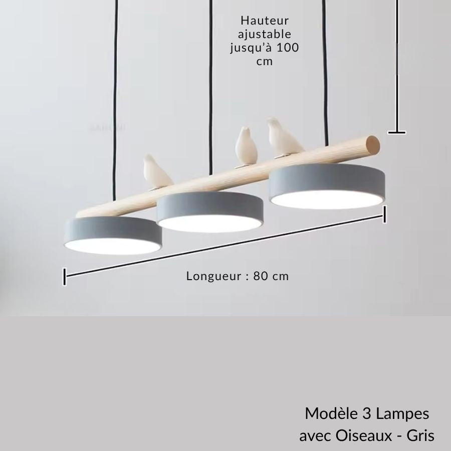 Des oiseaux blancs perchés sur le bois dominent trois disques gris dans ce lustre scandinave au dessin épuré