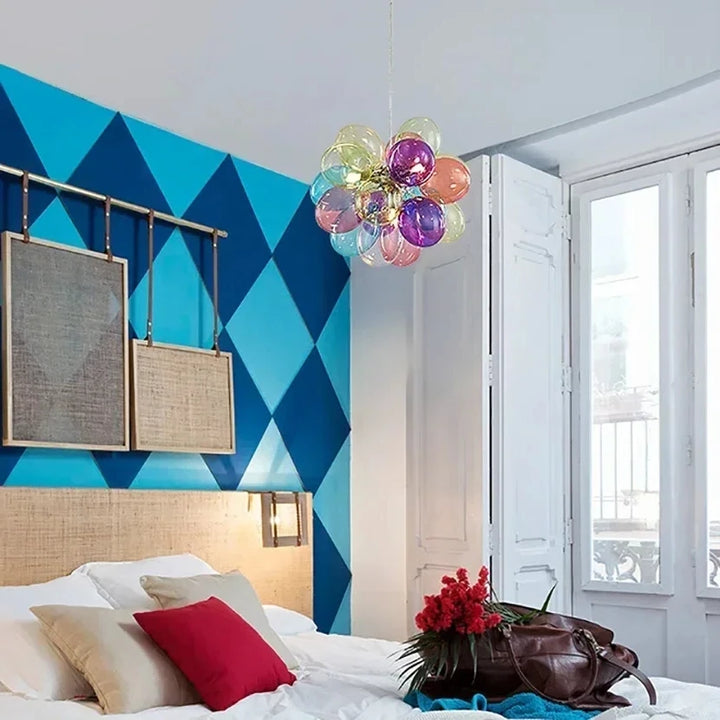 Lustre bohème en verre coloré translucide suspendu au-dessus d'un lit douillet avec coussins.