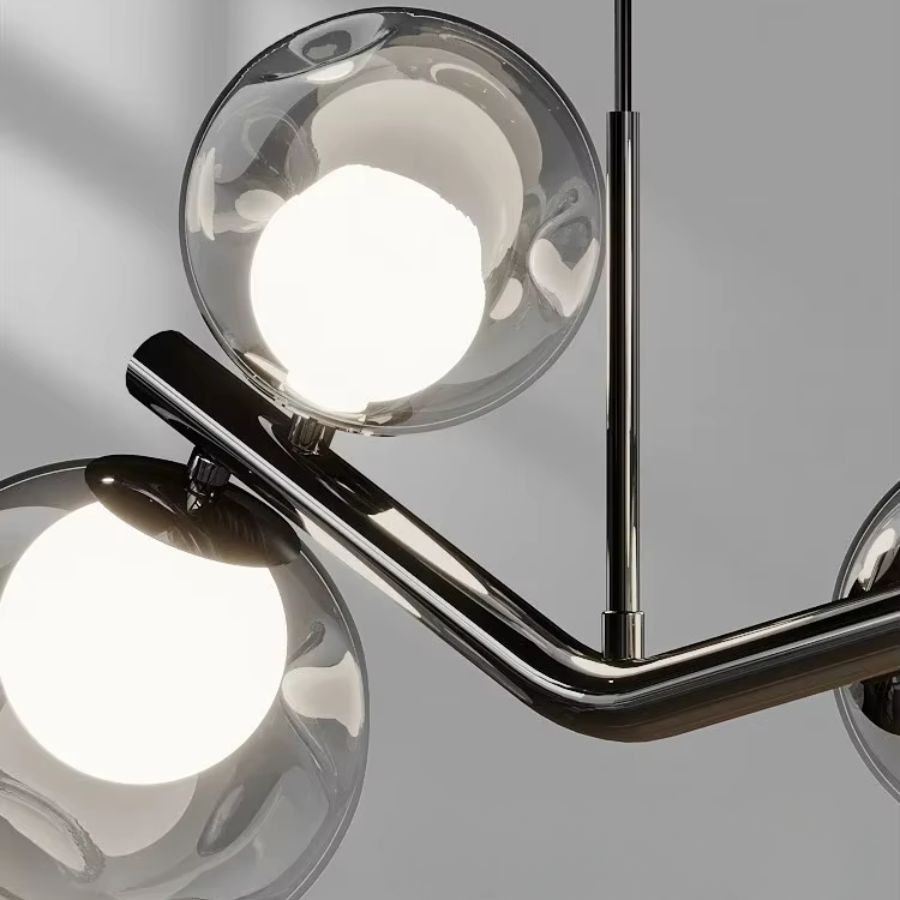 Détail d’un lustre branche à globes en verre avec structure noire brillante, au design sculptural et contemporain