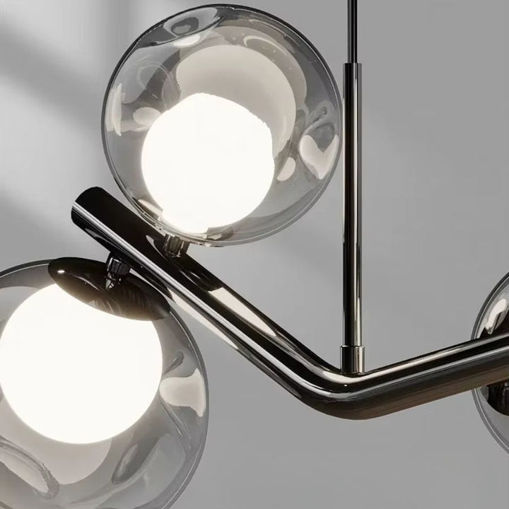 Détail d’un lustre branche à globes en verre avec structure noire brillante, au design sculptural et contemporain