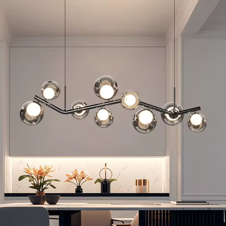 Lustre branche aux lignes organiques avec globes en verre, installé dans une salle à manger contemporaine