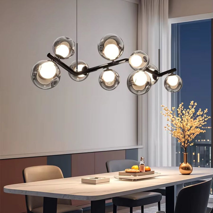Lustre branche à globes en verre fumé, au design organique et sculptural au-dessus d’une grande table de salle à manger
