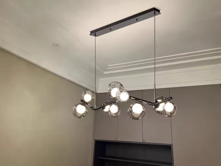 Lustre branche noir à globes en verre gris fumé, au style moderne et graphique suspendu sous une barre de plafond