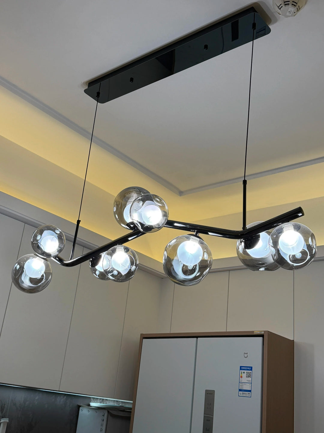 Lustre branche noir aux formes organiques avec globes en verre sculpté, installé dans une cuisine moderne