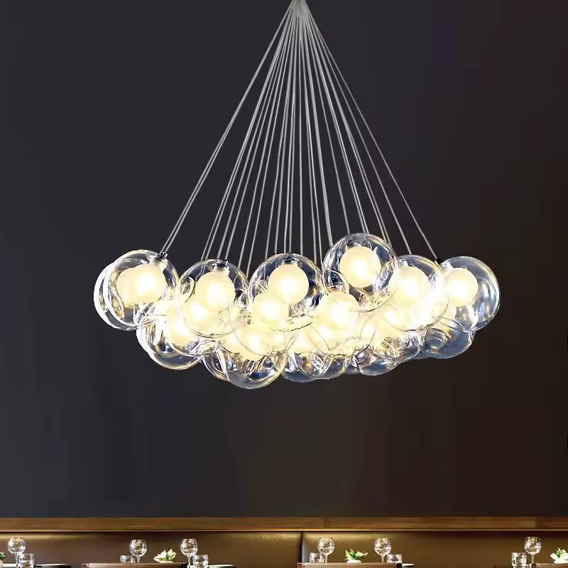 Lustre contemporain en grappe de bulles de verre transparent, suspendues par de fins câbles dans un esprit sculptural.