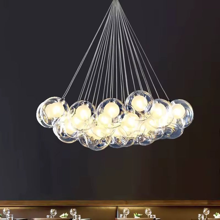 Lustre contemporain en grappe de bulles de verre transparent, suspendues par de fins câbles dans un esprit sculptural.