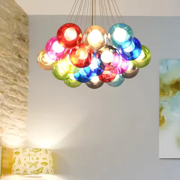 Grappe de bulles en verre rouge, bleu, rose et vert formant un lustre bulle original aux accents pop dans un intérieur moderne.
