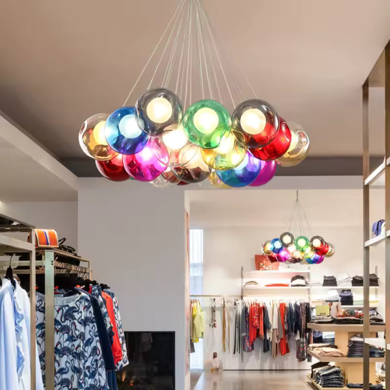 Lustre multicolore en grappe de bulles de verre teinté, aux reflets vifs et lumineux, dans une boutique contemporaine.