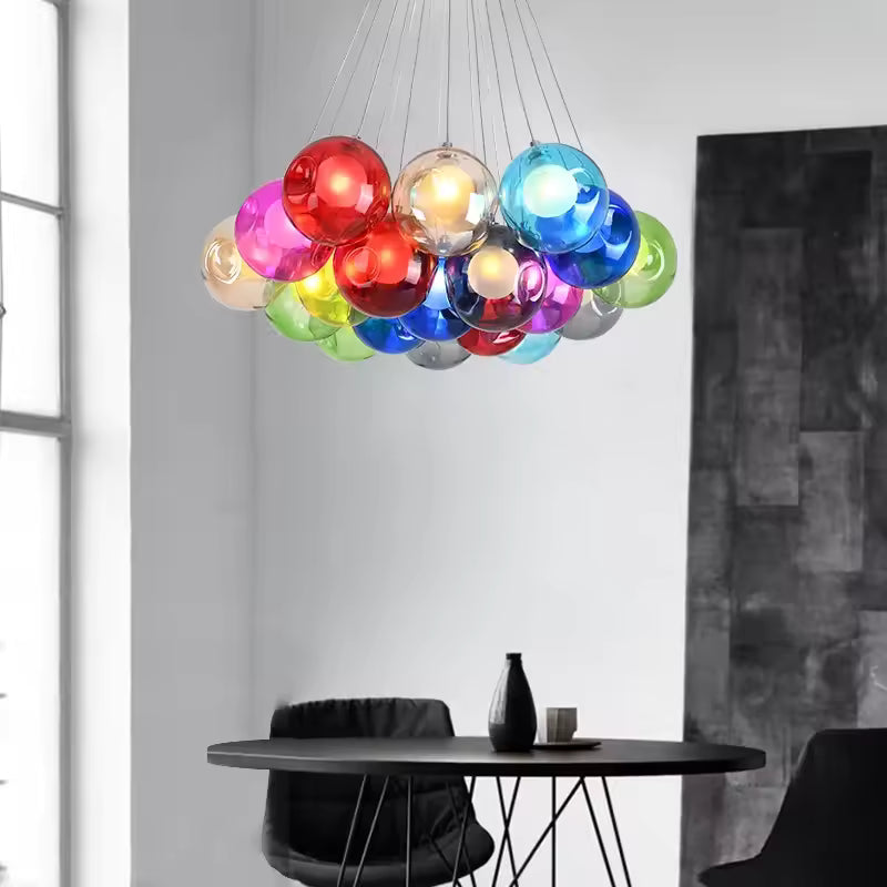 Une composition de globes en verre multicolore illumine ce lustre suspendu au-dessus d'une table noire, d'esprit pop art.
