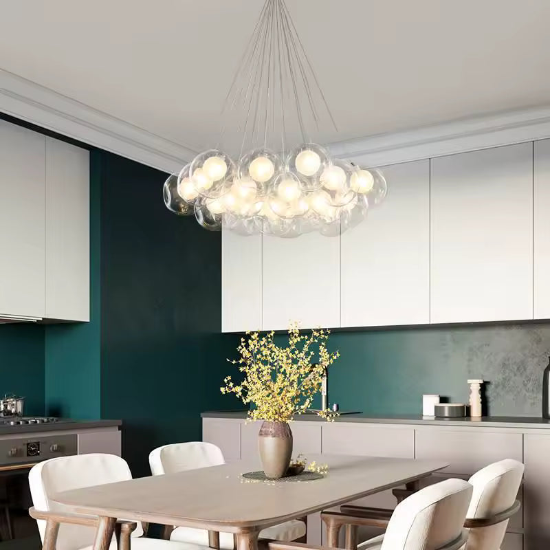 Au-dessus d'une table à manger, lustre design en cascade de bulles de verre transparent, à l'allure aérienne et moderne.