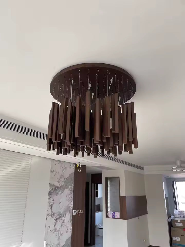 Lustre cascade en bois foncé au design contemporain, composé de tasseaux suspendus sous une large rosace ronde