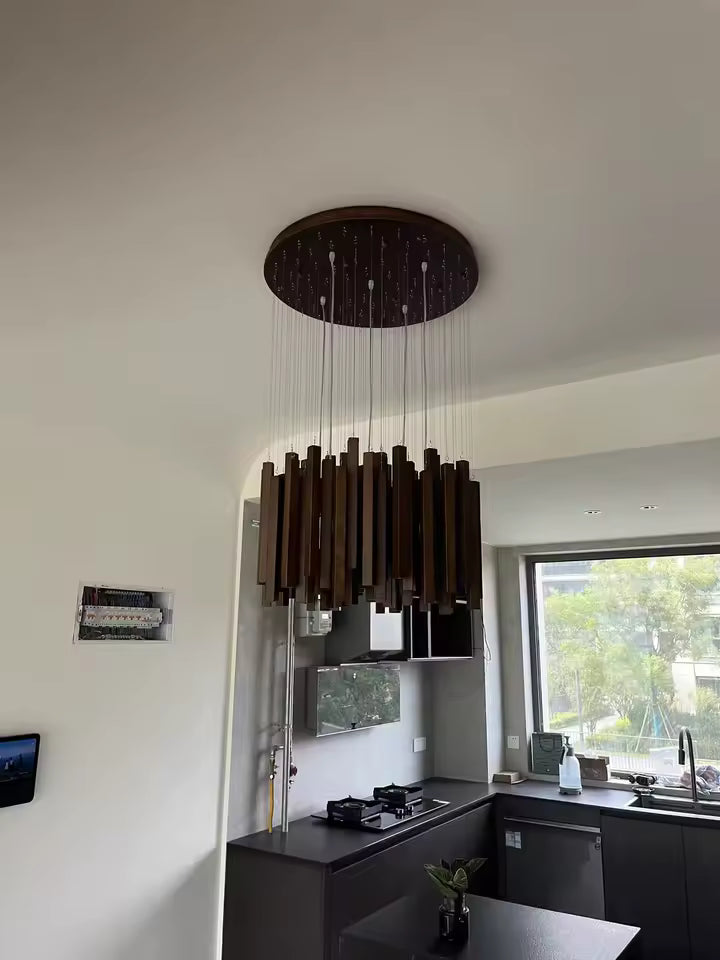 Suspension cascade en bois foncé au style organique, installée dans une cuisine moderne aux lignes sobres et chaleureuses