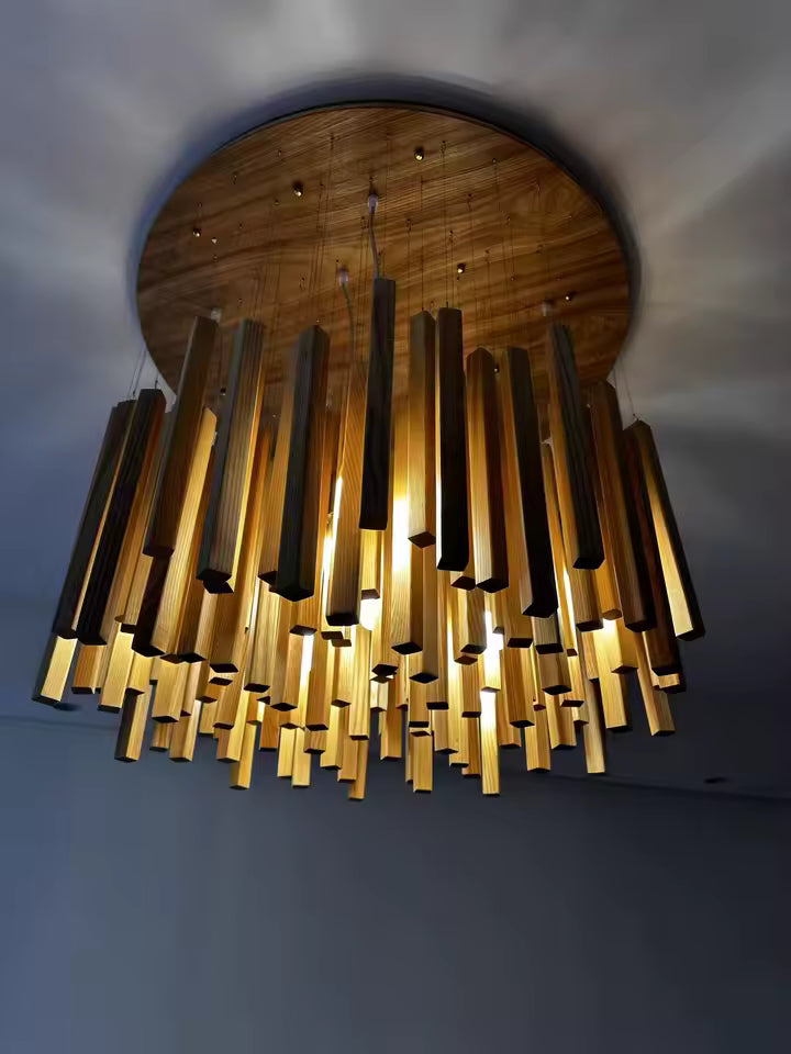 Vue en contre-plongée d’un lustre cascade en bois massif, au design organique sublimé par une lumière chaude