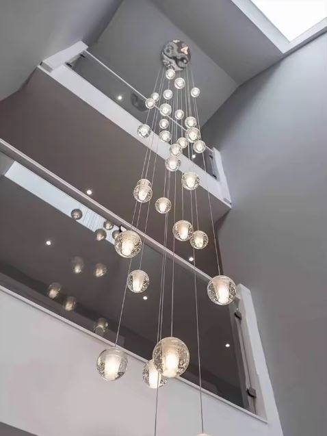 Lustre en cascade de boules en verre suspendues, idéal pour cage d’escalier et intérieur design architectural.
